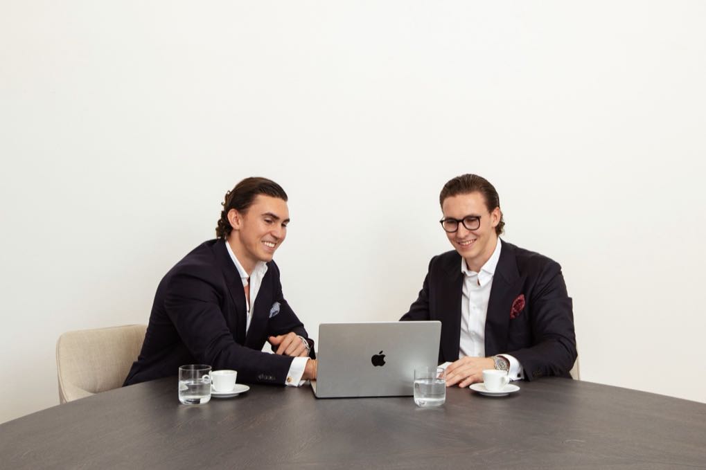 Jürgen and Matthias Nussbaumer smiling at a meeting table in front of a laptop