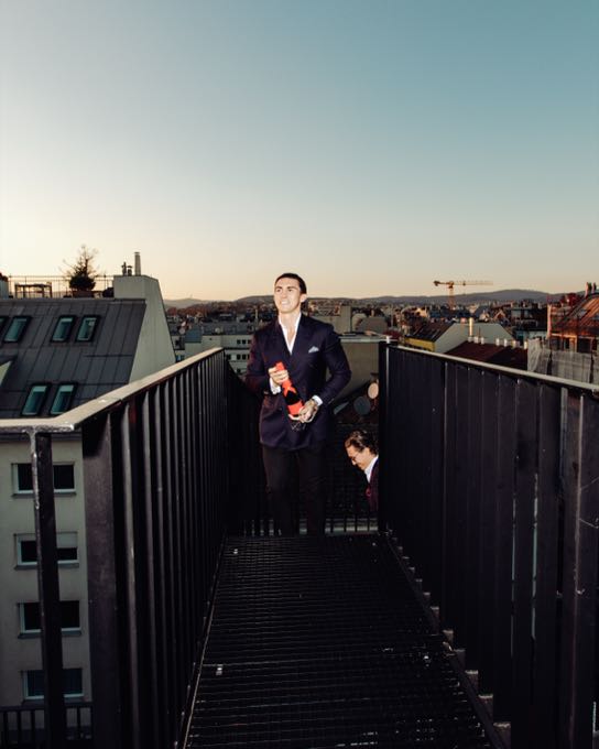 Man in a suit on a rooftop terrace overlooking the city roofs