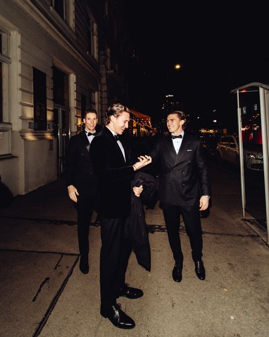 Three men in dinner jackets on a street at night