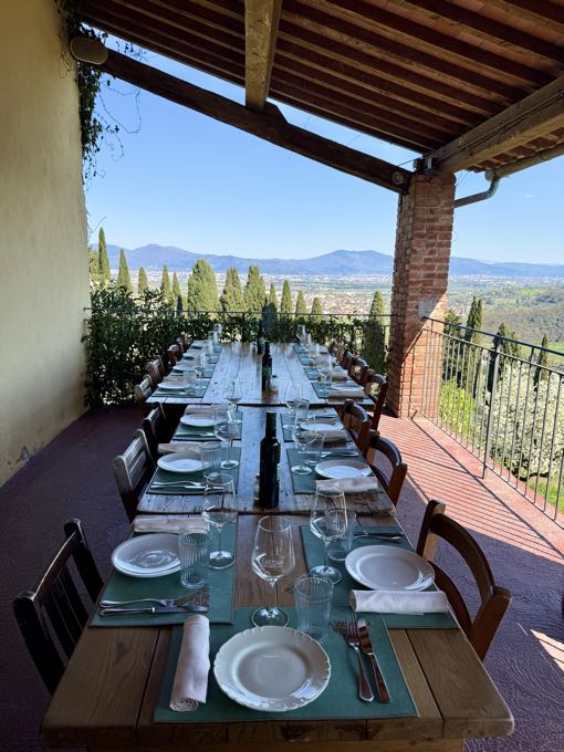 Long table laid on a covered terrace overlooking rolling hills