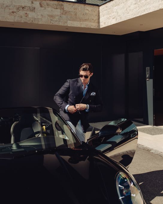 Man in a suit getting into a sports car in a garage