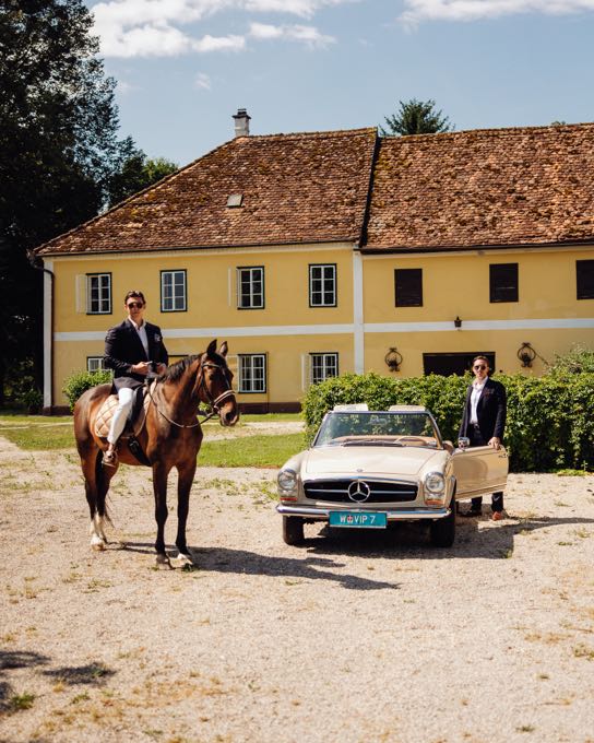 Rider and a classic car in front of a yellow country house