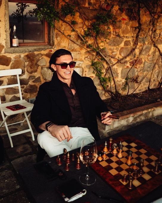 Man in sunglasses playing chess in front of a stone wall