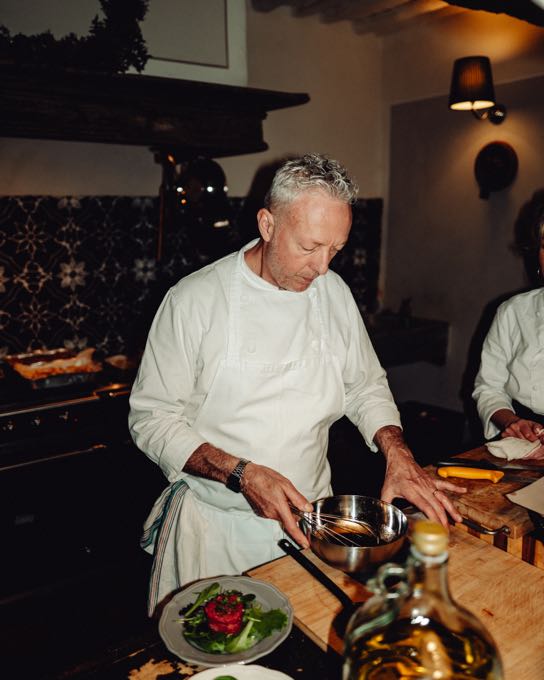 Chef in a white jacket plating dishes in a kitchen