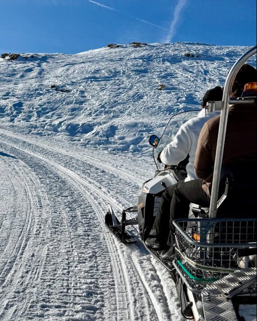 Snowmobile ride across a snowy slope under a blue sky
