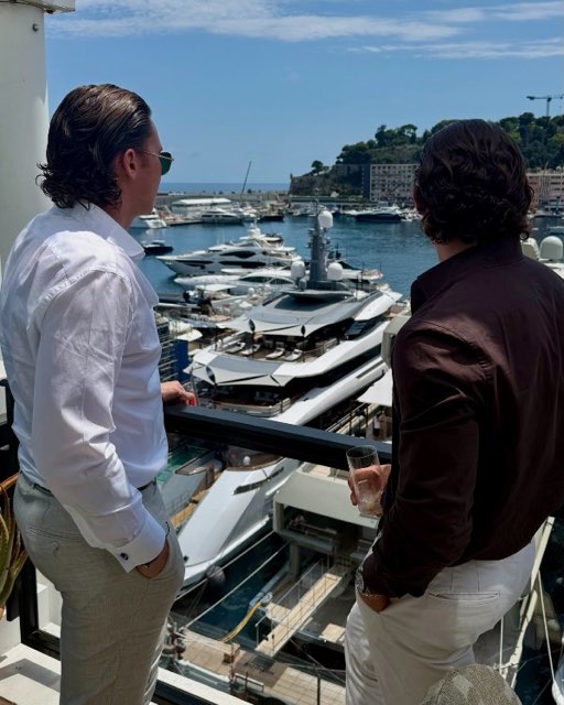 Two men in conversation overlooking yachts in the harbour
