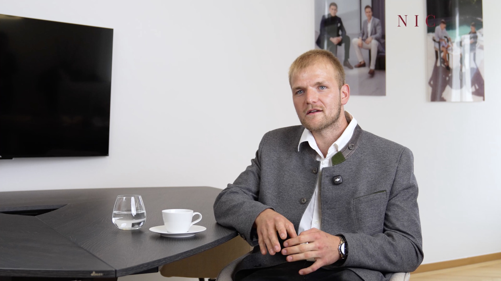 Sandro S. im grauen Trachtensakko sitzt im NIC Büro an einem dunklen Tisch und erzählt